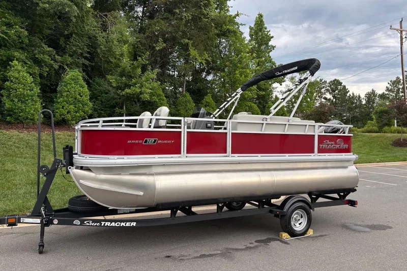 Slide: The Image of 2026 Sun Tracker Bass Buggy 18 DLX pontoon boat on trailer, parked outdoors. - 1