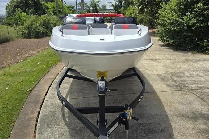 Slide: The Image of 2026 Tahoe T21 boat on trailer, parked on driveway, surrounded by greenery. - 2