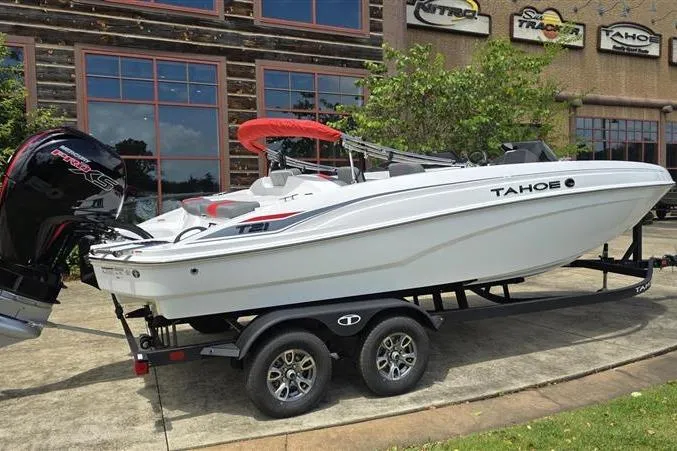Slide: The Image of 2026 Tahoe T21 boat on trailer, parked outside a building with branded signage. - 7