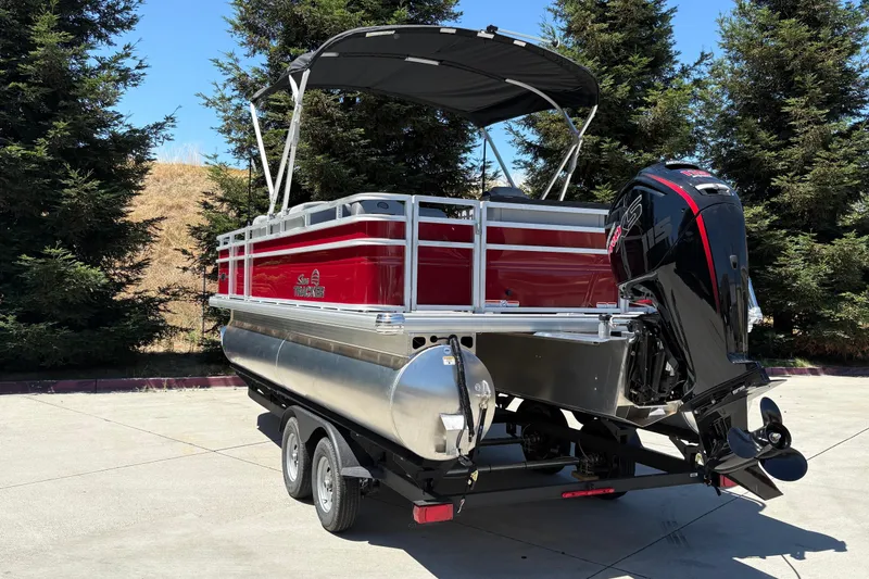 Slide: The Image of 2026 Sun Tracker SportFish 20 DLX pontoon boat with outboard motor, parked outdoors. - 4