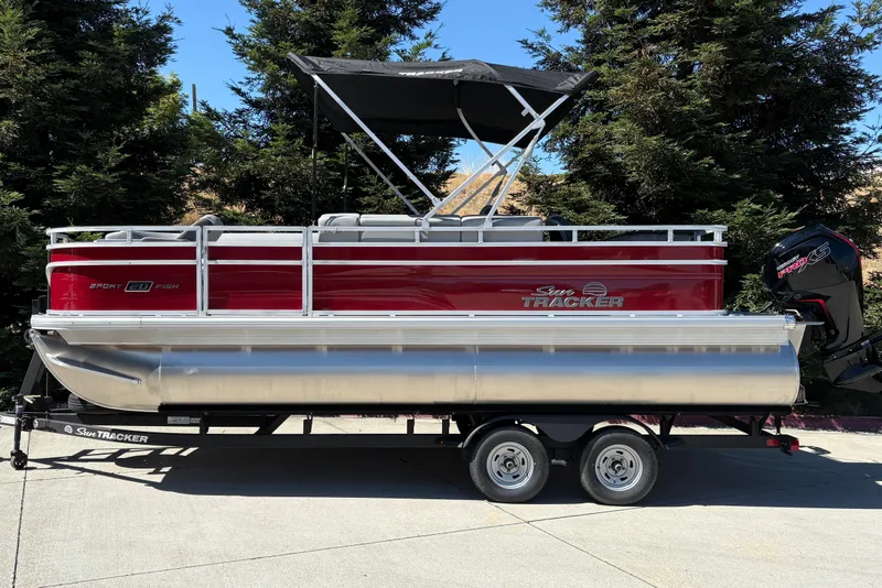 The Image of 2026 Sun Tracker SportFish 20 DLX pontoon boat on trailer, parked outdoors. - 0