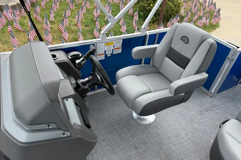 Slide: The Image of 2026 Sun Tracker Party Barge 18 DLX interior with captain's chair and control console. - 16