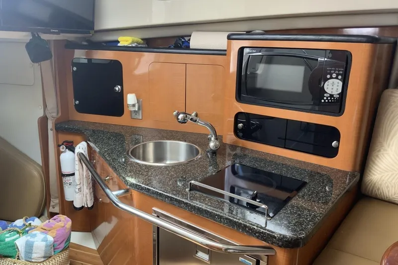 Slide: The Image of 2007 Robalo R305 Walkaround boat interior kitchen with sink, microwave, and stove. - 10