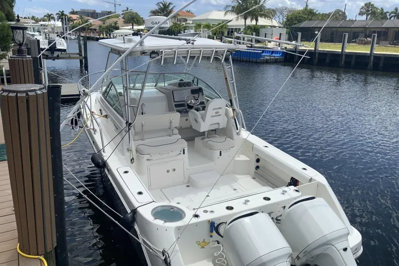 Slide: The Image of 2007 Robalo R305 Walkaround boat docked by a canal, featuring dual outboard engines. - 16