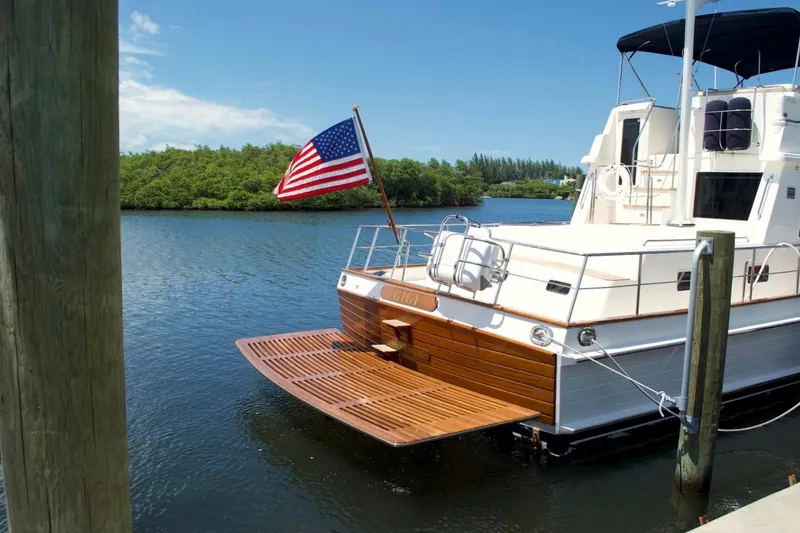 Slide: The Image of 2009 Grand Banks 47 Heritage CL yacht docked, featuring a wooden swim platform and American flag. - 8