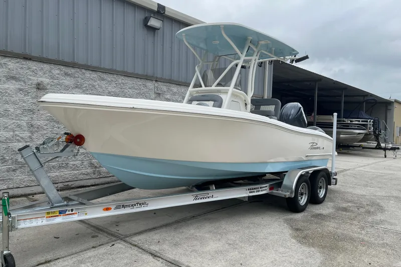 Slide: The Image of 2026 Pioneer 202 Islander boat on trailer, parked outdoors near a metal building. - 17