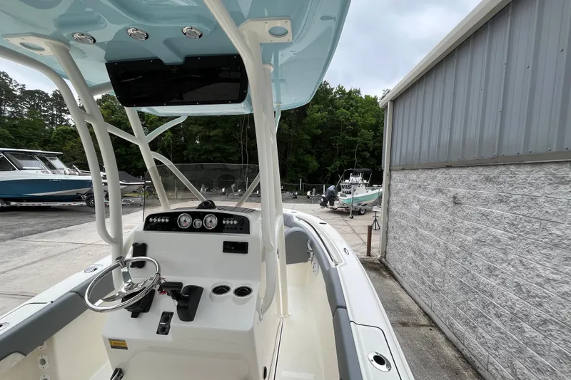 Slide: The Image of 2026 Pioneer 202 Islander boat interior with steering console, docked outdoors. - 23