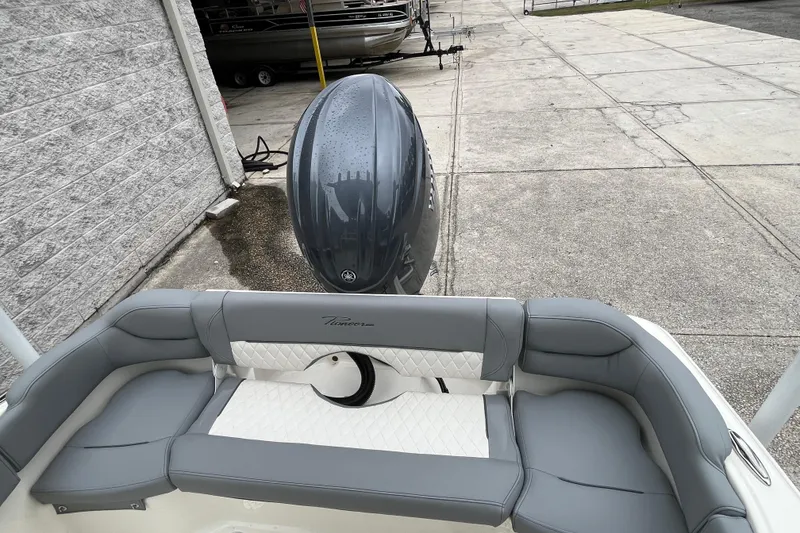 Slide: The Image of 2026 Pioneer 202 Islander boat with gray seating and outboard motor in a driveway. - 26