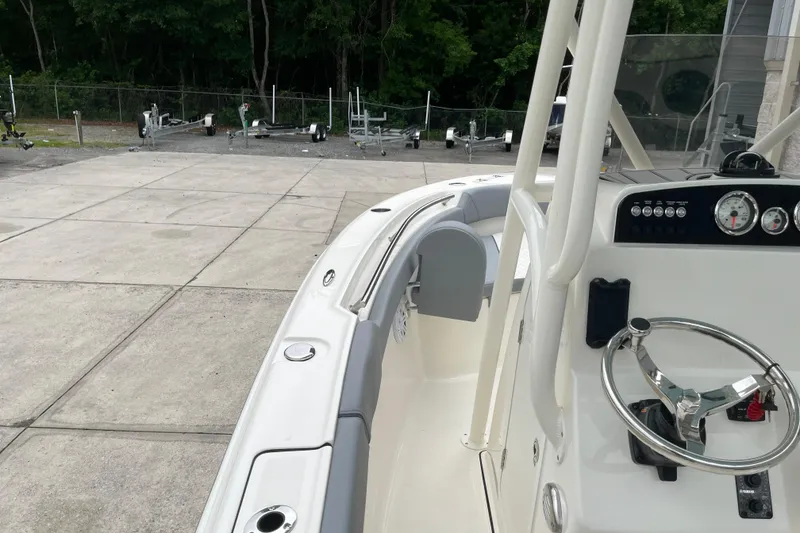 Slide: The Image of 2026 Pioneer 202 Islander boat interior with steering wheel and dashboard, parked on concrete. - 8