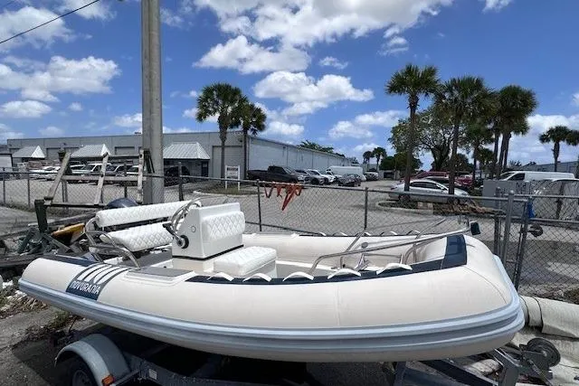 The Image of 2015 Novurania DL 460 inflatable boat on trailer, parked outdoors under a blue sky. - 1