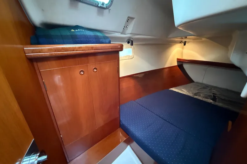 Slide: The Image of Cozy cabin interior of 2005 Beneteau 331 sailboat with wooden cabinetry and blue bedding. - 11