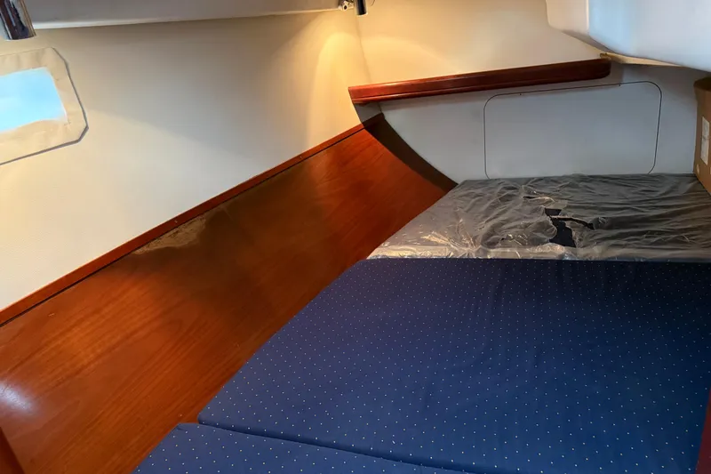 Slide: The Image of Cozy cabin interior of 2005 Beneteau 331 sailboat with wooden paneling and blue bedding. - 12