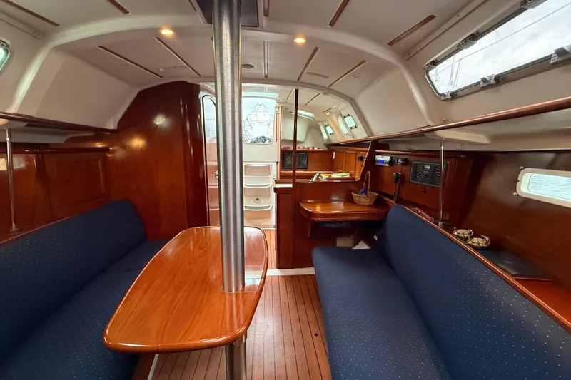 Slide: The Image of Interior of a 2005 Beneteau 331 sailboat with wooden finishes and blue seating. - 8