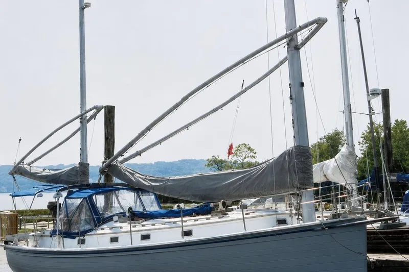 Slide: The Image of 1983 Nonsuch Cat Ketch sailboat docked, featuring dual masts and covered sails. - 1