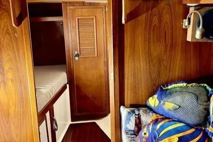 Slide: The Image of 1983 Nonsuch Cat Ketch interior with wooden finish and colorful fish-themed pillows. - 12