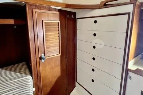 Slide: The Image of Interior of 1983 Nonsuch Cat Ketch with wooden cabinetry and striped bedding. - 14