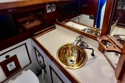 Slide: The Image of 1983 Nonsuch Cat Ketch bathroom with brass sink and wooden accents. - 15