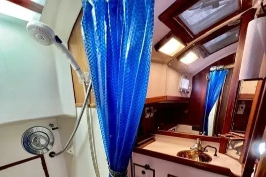 Slide: The Image of Interior of 1983 Nonsuch Cat Ketch sailboat bathroom with shower and blue curtain. - 17