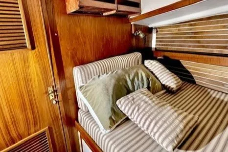 Slide: The Image of Cozy cabin interior of 1983 Nonsuch Cat Ketch with striped bedding and wooden accents. - 19