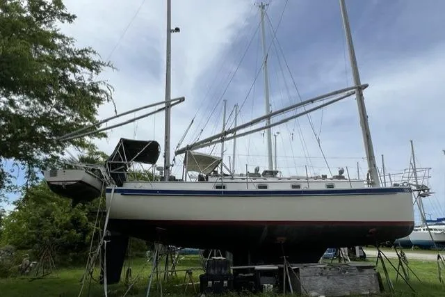 Slide: The Image of 1983 Nonsuch Cat Ketch sailboat on land, surrounded by trees and other boats. - 2