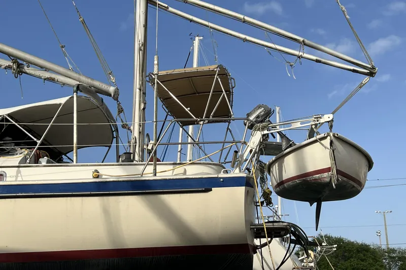 Slide: The Image of 1983 Nonsuch Cat Ketch sailboat with dinghy, docked under clear blue sky. - 25