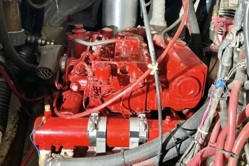 Slide: The Image of Red engine of a 1983 Nonsuch Cat Ketch sailboat, surrounded by cables and hoses. - 27