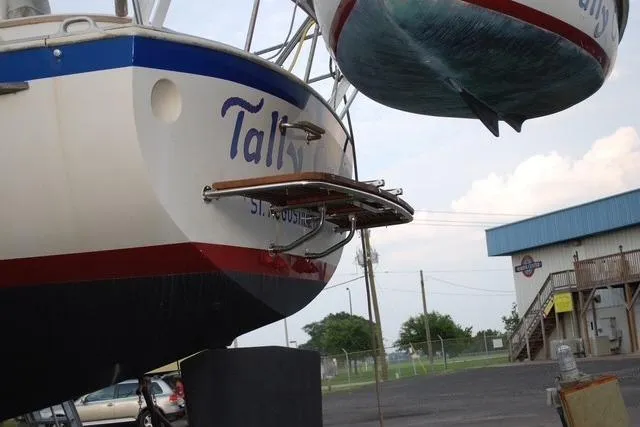 Slide: The Image of 1983 Nonsuch Cat Ketch sailboat in dry dock, showcasing stern and marina background. - 4