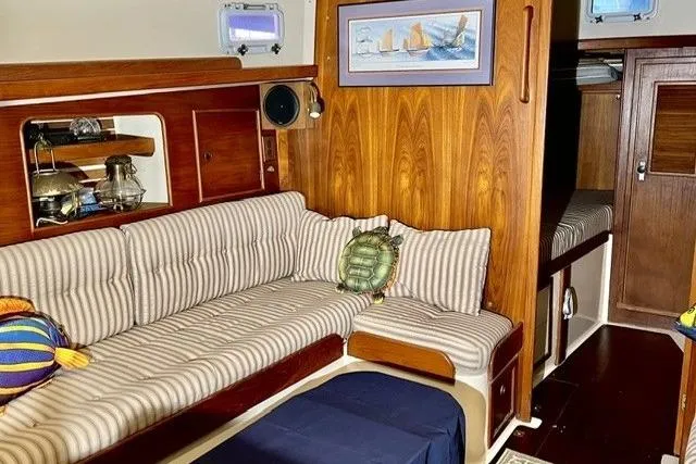 Slide: The Image of Interior of a 1983 Nonsuch Cat Ketch sailboat with striped seating and nautical decor. - 6