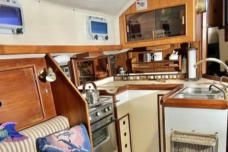 Slide: The Image of 1983 Nonsuch Cat Ketch interior with wood cabinetry, compact kitchen, and nautical decor. - 9