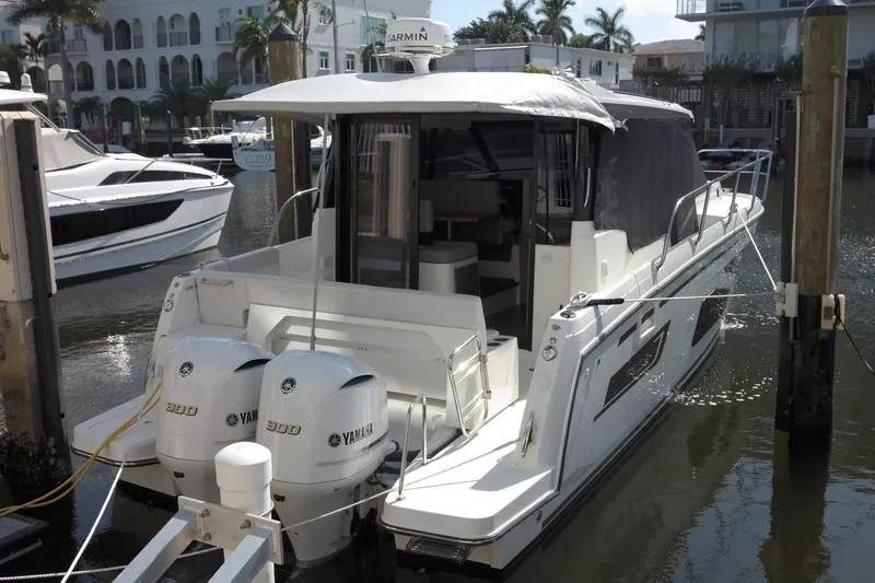 Slide: The Image of 2020 Jeanneau NC 1095 Coupe docked, featuring twin Yamaha 300 engines, in a marina setting. - 2