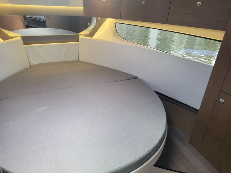 Slide: The Image of 2020 Jeanneau NC1095 cabin interior with round bed and window view. - 32