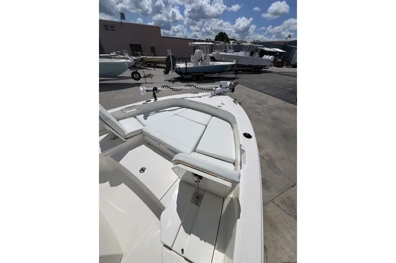 Slide: The Image of 2023 Pathfinder 2400 TRS boat with white seating, docked under a partly cloudy sky. - 16