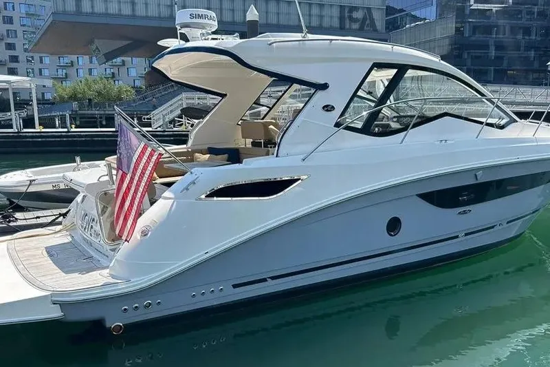 The Image of 2019 Sea Ray Sundancer 350 Coupe docked, featuring sleek design and American flag. - 0