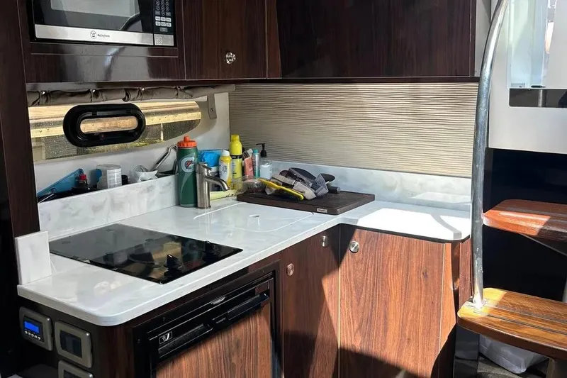 Slide: The Image of 2019 Sea Ray Sundancer 350 Coupe kitchen with modern appliances and sleek wooden cabinetry. - 21