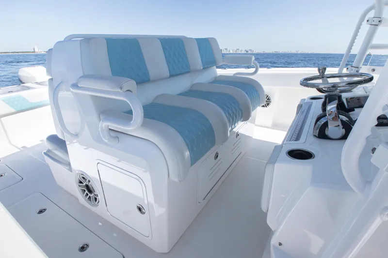 Slide: The Image of 2019 Invincible 40 Catamaran interior with blue and white seating, steering wheel, and ocean view. - 15