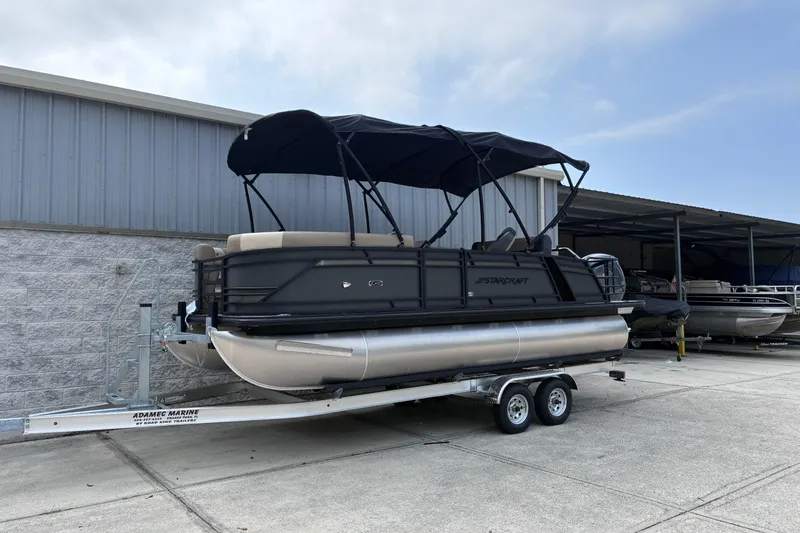 Slide: The Image of 2026 Starcraft EXS 1 Q DH pontoon boat on trailer, parked outdoors. - 2
