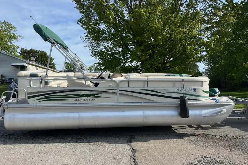 The Image of 2004 Bennington 2250RL pontoon boat parked on a street with lush green trees. - 0