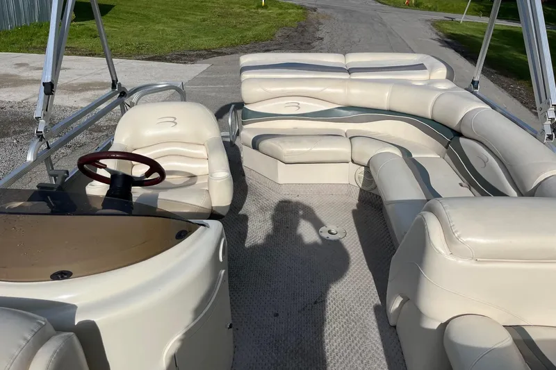 Slide: The Image of 2004 Bennington 2250RL pontoon boat interior with beige seating and steering wheel. - 13