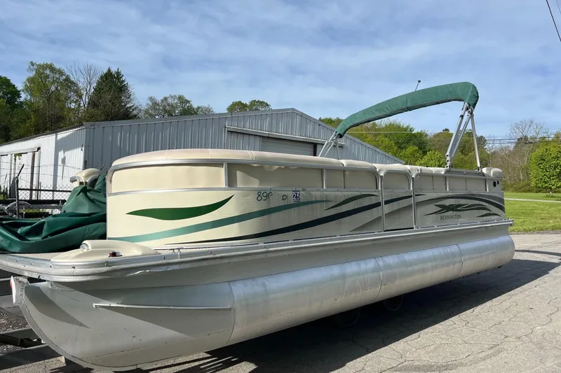 Slide: The Image of 2004 Bennington 2250RL pontoon boat with green canopy, parked outdoors. - 2
