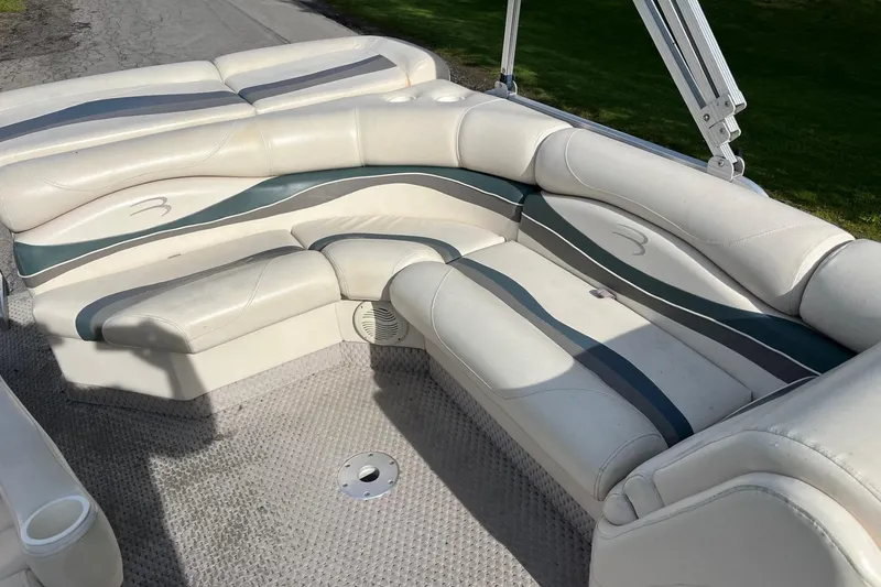 Slide: The Image of 2004 Bennington 2250RL boat interior with white and gray seating on a sunny day. - 4