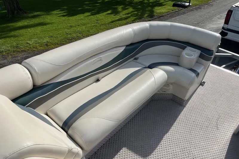 Slide: The Image of 2004 Bennington 2250RL boat seating with cup holders, featuring cream and gray upholstery. - 6