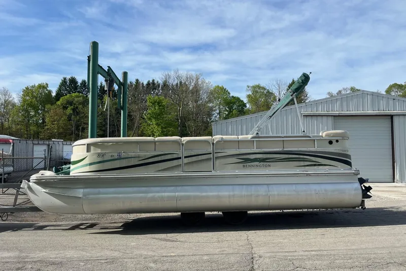 Slide: The Image of 2004 Bennington 2250RL pontoon boat parked near a metal building under a clear sky. - 7