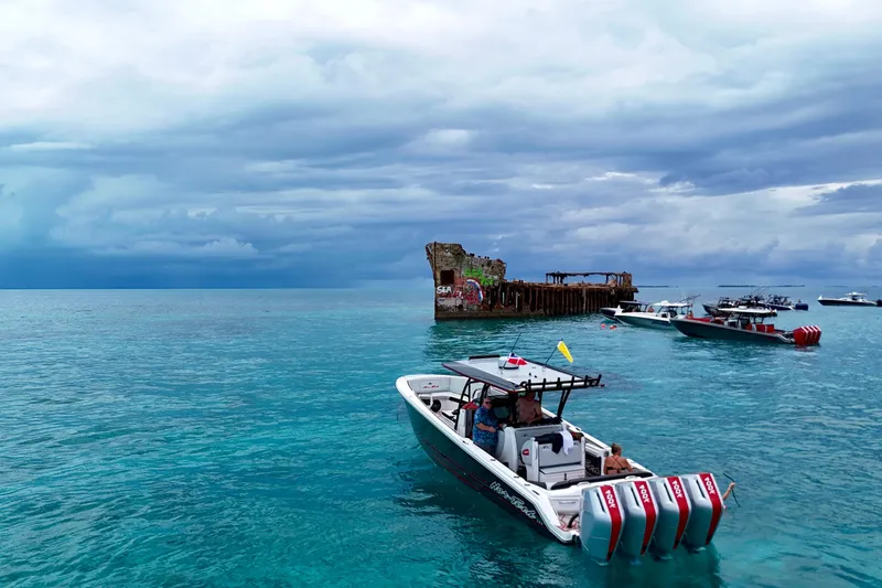 Slide: The Image of Nor-Tech 390 Sport Center Console 2026 cruising near a shipwreck in clear blue waters. - 5