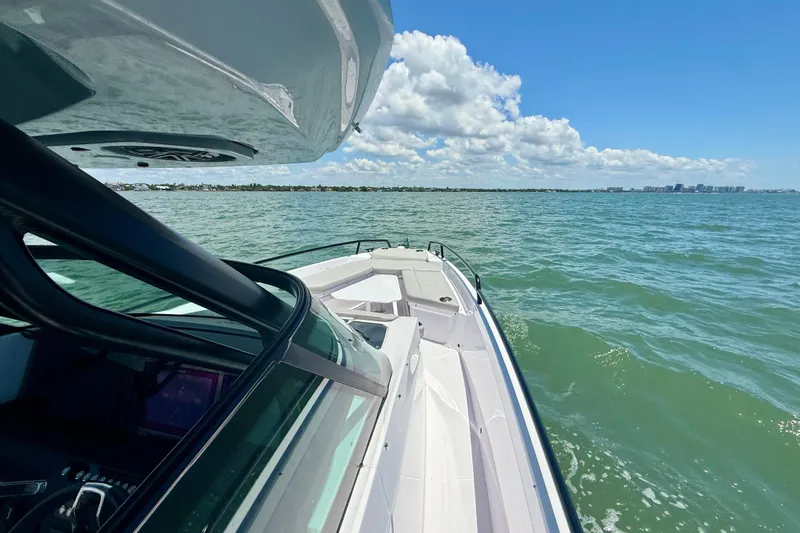 Slide: The Image of 2025 Axopar 29 Sun-Top cruising on open water under a clear blue sky. - 14