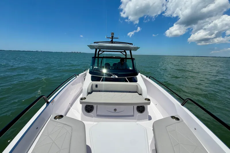 Slide: The Image of 2025 Axopar 29 Sun-Top boat cruising on open water under a clear blue sky. - 19