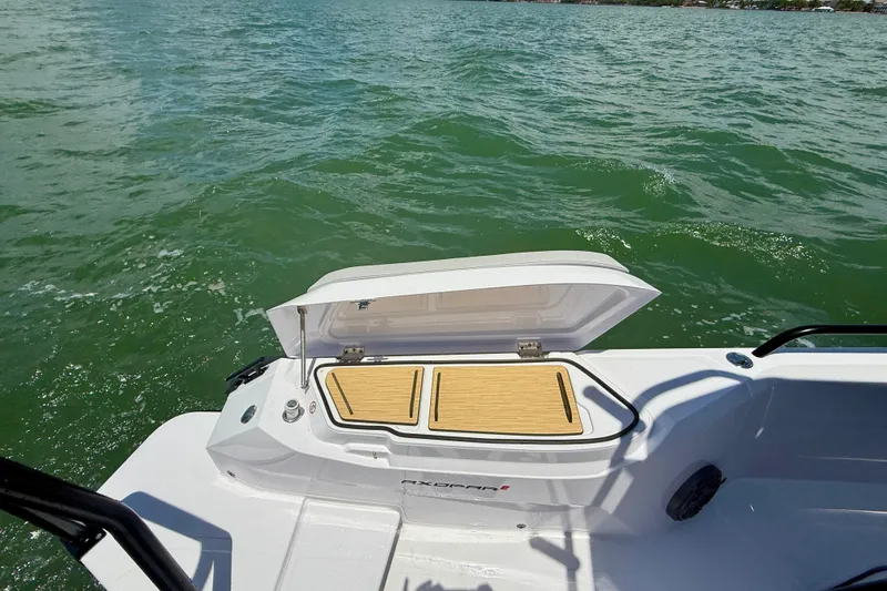 Slide: The Image of 2025 Axopar 29 Sun-Top boat with open storage compartment on calm water. - 3