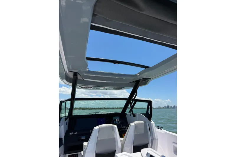 Slide: The Image of 2025 Axopar 29 Sun-Top boat interior with open roof, overlooking ocean and skyline. - 9