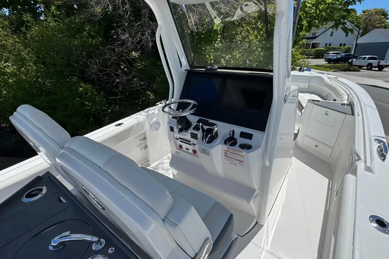 Slide: The Image of 2026 Edgewater 262CC boat cockpit with modern controls and seating, surrounded by greenery. - 24