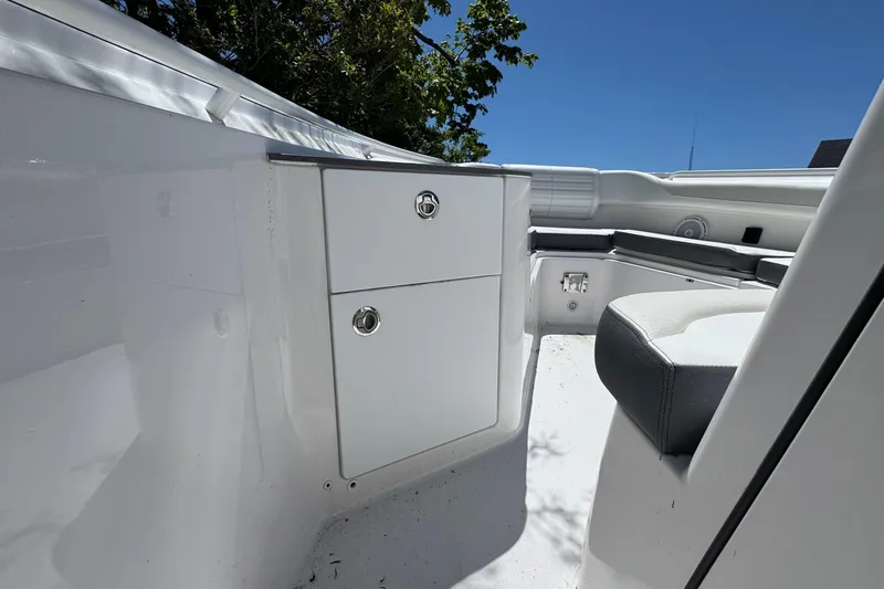 Slide: The Image of 2026 Edgewater 262CC boat interior with storage compartments and seating under clear blue sky. - 28