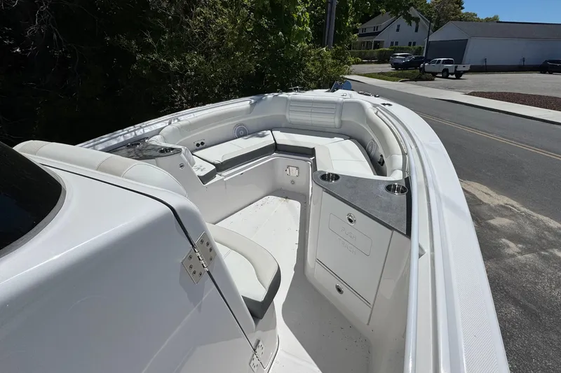 Slide: The Image of 2026 Edgewater 262CC boat interior with white seating and cup holders, parked near trees. - 31